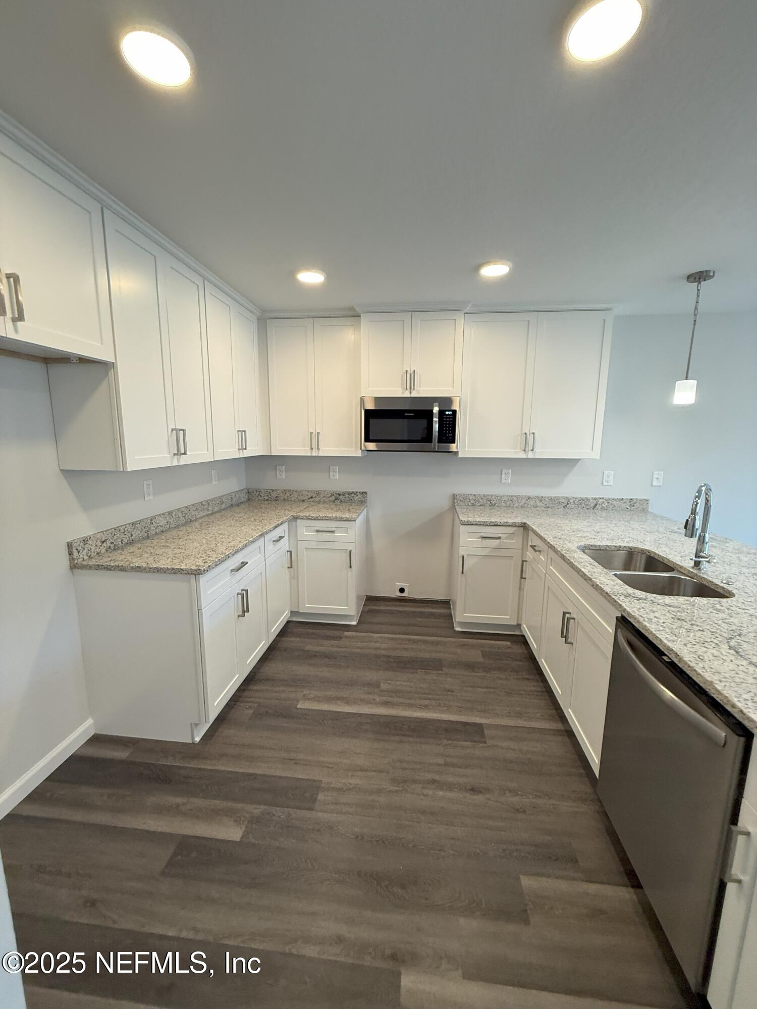 8822 Orme Road Jacksonville, FL 32220 - Photo 18 of 26 a large white kitchen with stainless steel appliances granite countertop a stove a sink a refrigerator white cabinets and wooden floor