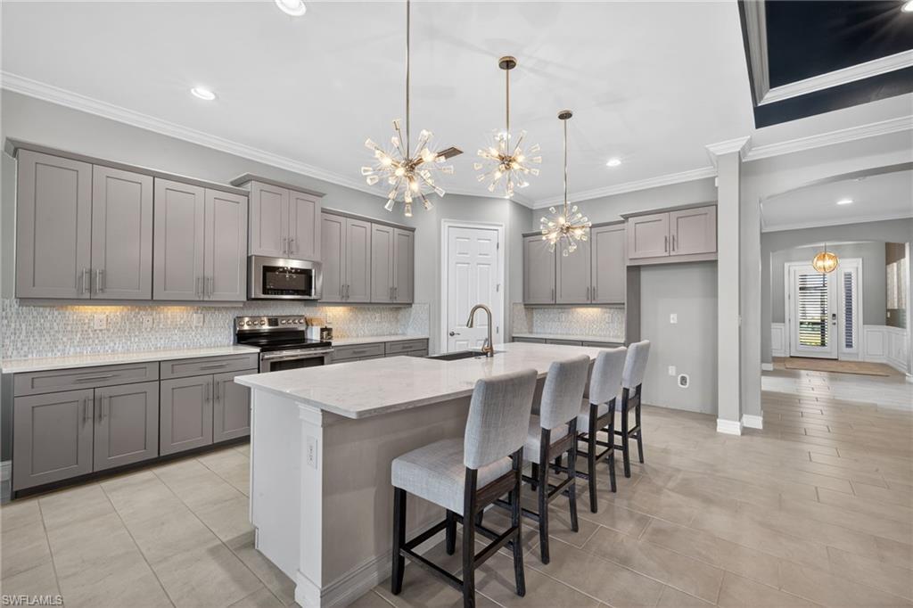14748 Windward Lane Naples, FL 34114 - Photo 16 of 50 a kitchen with stainless steel appliances kitchen island granite countertop a dining table chairs and white cabinets