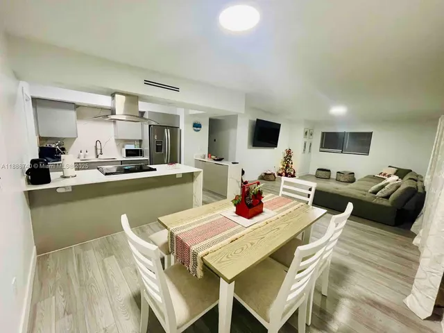 a living room with stainless steel appliances furniture and a kitchen view