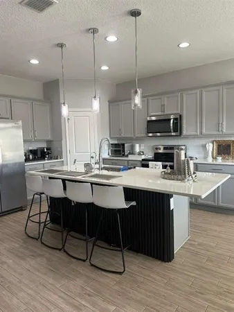 a kitchen with kitchen island granite countertop a sink counter and chairs