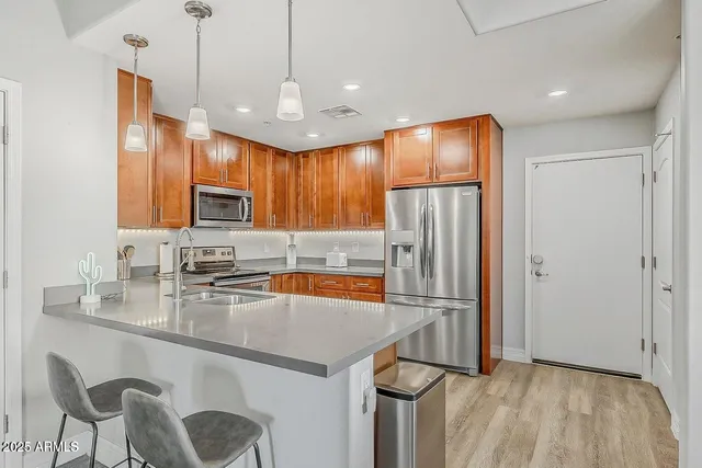 a kitchen with stainless steel appliances granite countertop a refrigerator a sink a stove a dining table and chairs