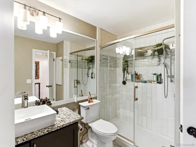 a bathroom with a granite countertop sink toilet mirror and shower