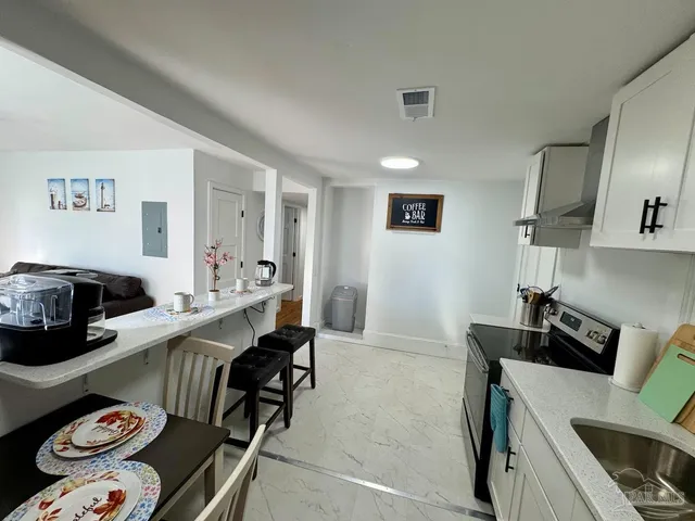 a room with a couch a rug and a view of kitchen