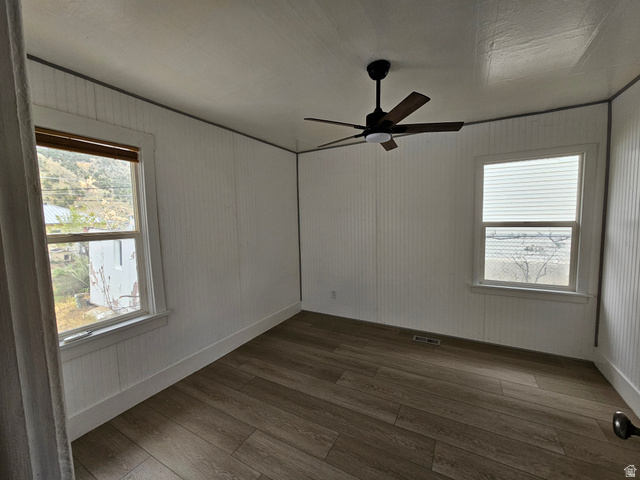 744 Royal Street Helper, UT 84526 - Photo 7 of 33 Empty room featuring ceiling fan, dark wood-style floors, and wood walls