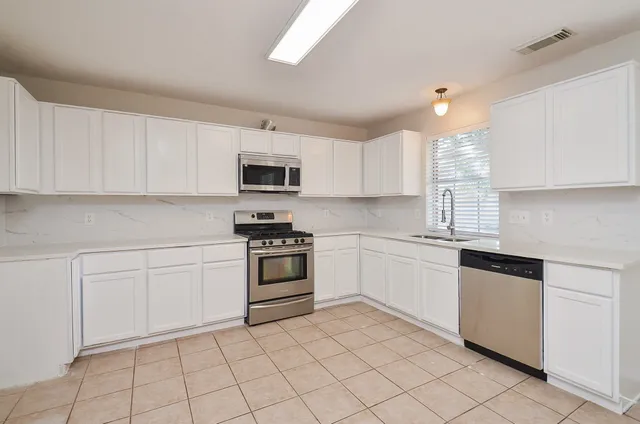 a view of an empty room with window and chandelier fan