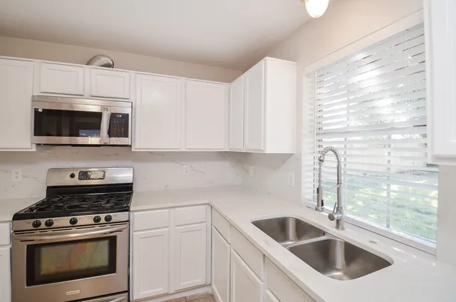 an empty room with wooden floor chandelier fan and windows