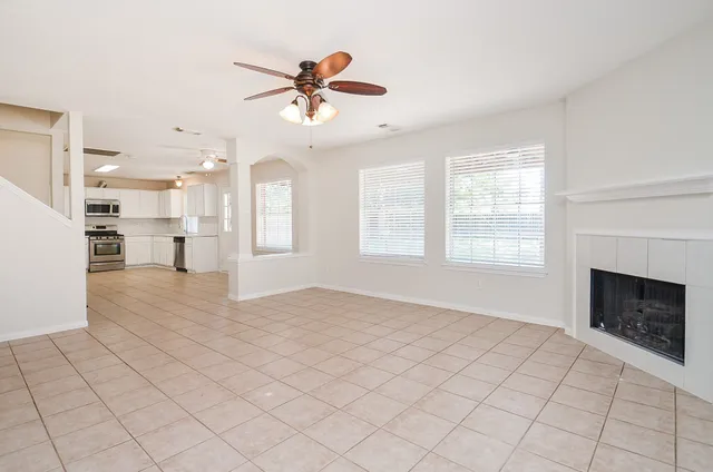 an empty room with wooden floor ceiling fan and windows