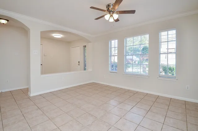 an empty room with chandelier fan and windows