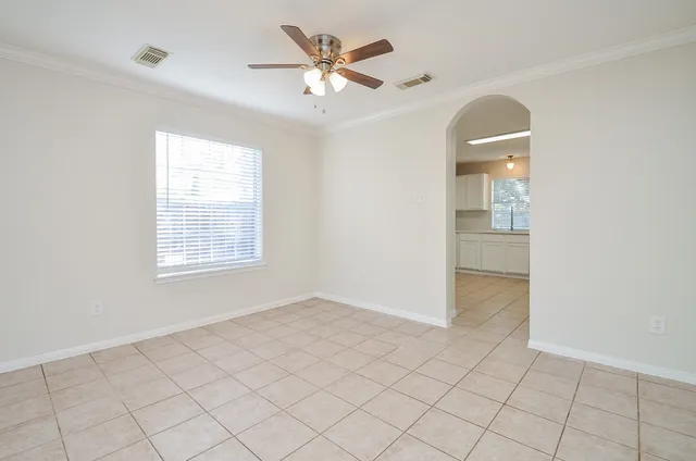 an empty room with chandelier fan and windows