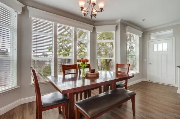 a kitchen with stainless steel appliances granite countertop a refrigerator oven a stove a dining table and chairs with wooden floor
