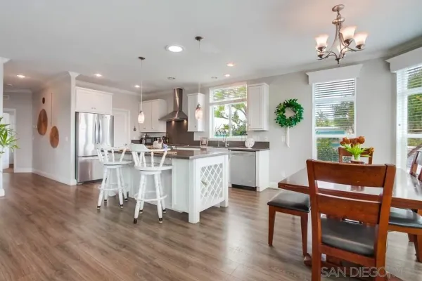 a kitchen with stainless steel appliances a stove a sink a refrigerator dining table and chairs