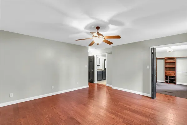 an empty room with windows and ceiling fan