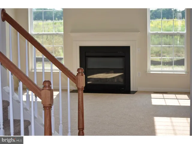 a view of an empty room with wooden floor and a fireplace