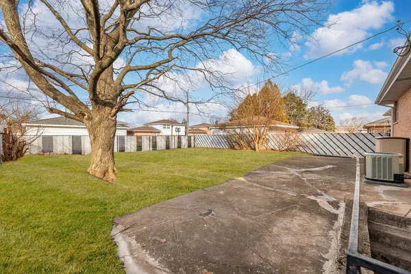 a view of a yard in front of a house with a large tree