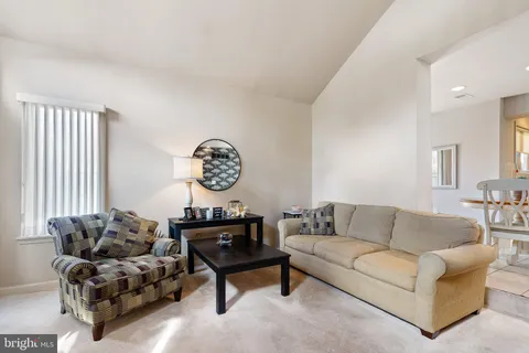 a living room with furniture a clock on wall and a window