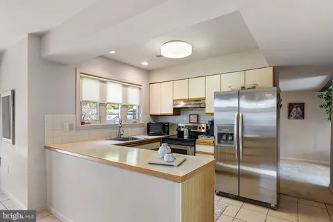 a kitchen with stainless steel appliances granite countertop a refrigerator a sink a stove a washer dryer and a refrigerator