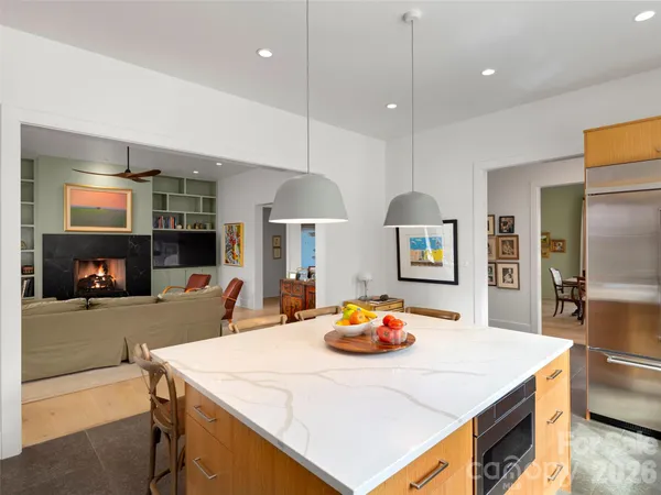 a kitchen island with stainless steel appliances a table chairs and a refrigerator