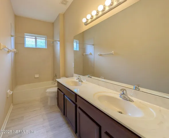 a bathroom with a granite countertop sink a toilet and shower
