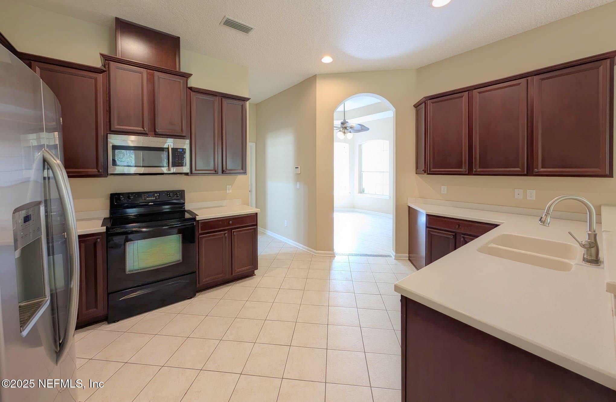 5871 Brush Hollow Road Jacksonville, FL 32258 - Photo 2 of 40 a kitchen with granite countertop a stove a microwave a sink and a refrigerator