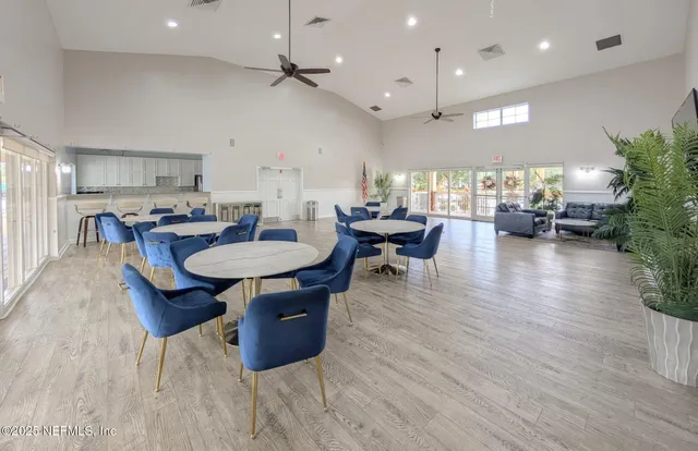 an open kitchen with granite countertop a stove a sink a dining table and chairs with wooden floor