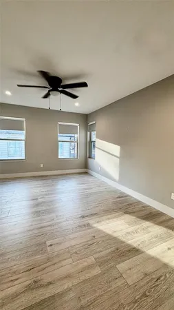 a view of empty room with wooden floor and fan