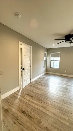 a view of empty room with wooden floor and fan