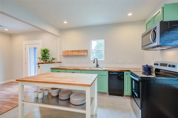 a kitchen with stainless steel appliances granite countertop a sink a stove a microwave a counter top space and cabinets