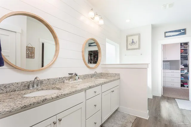 a bathroom with a granite countertop double vanity sink and a mirror