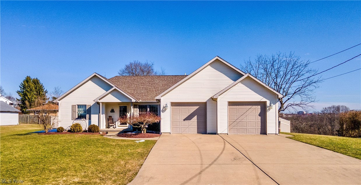 Ranch-style house featuring covered porch, a front yard, and a garage