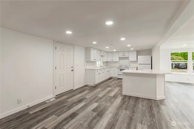 a large white kitchen with a white wooden cabinets and wooden floor