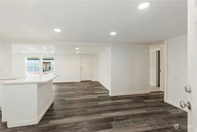 a view of kitchen and empty room with wooden floor