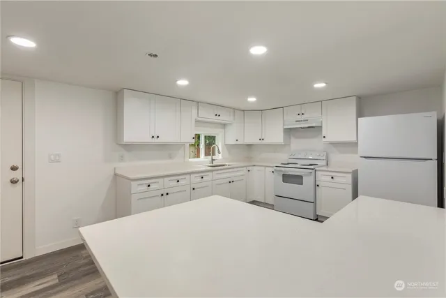 a kitchen with white cabinets white appliances and sink