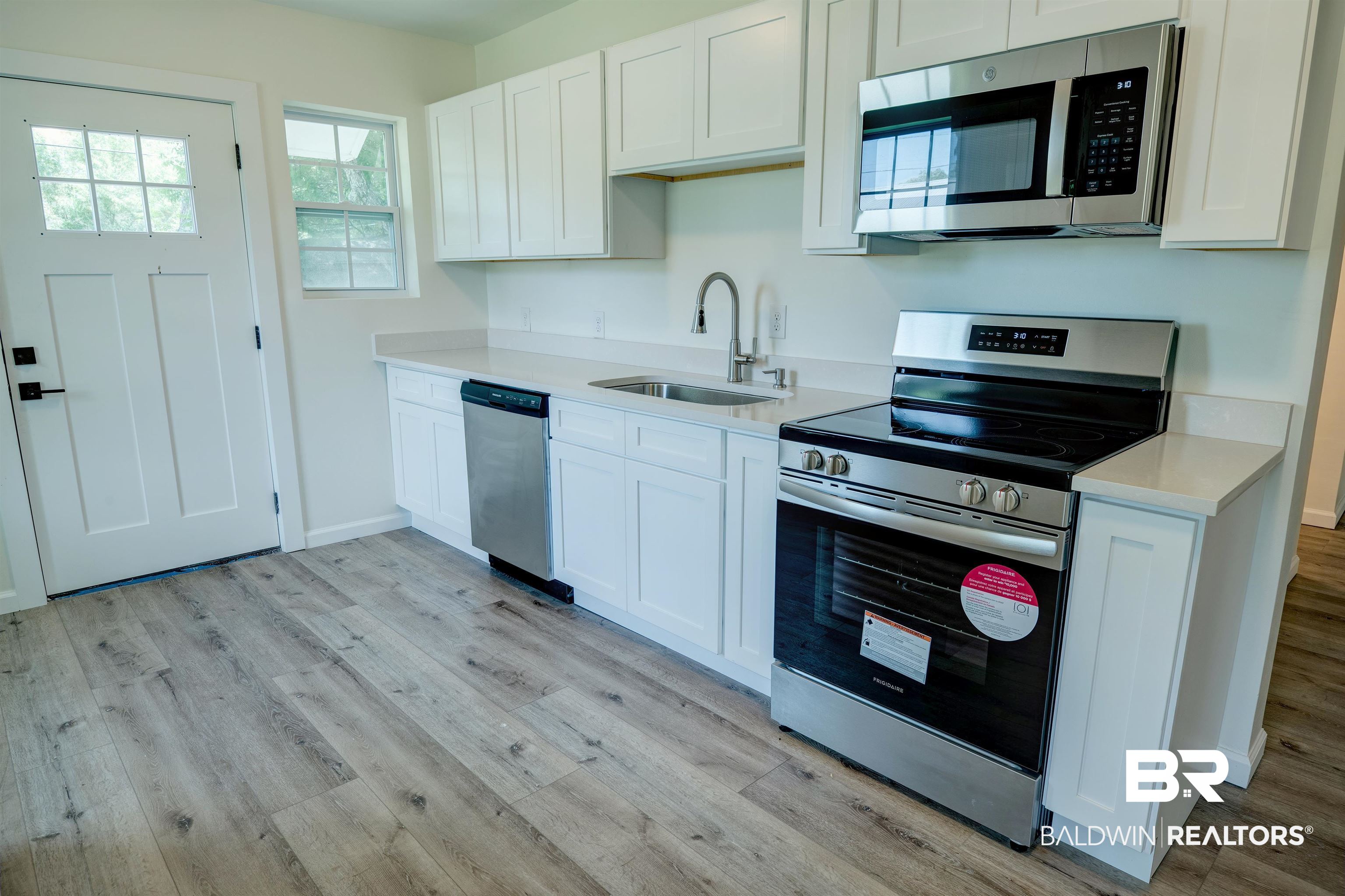 510 East Myrtle Avenue Foley, AL 36535 - Photo 8 of 22 Kitchen with appliances with stainless steel finishes, light wood finished floors, light countertops, and white cabinetry