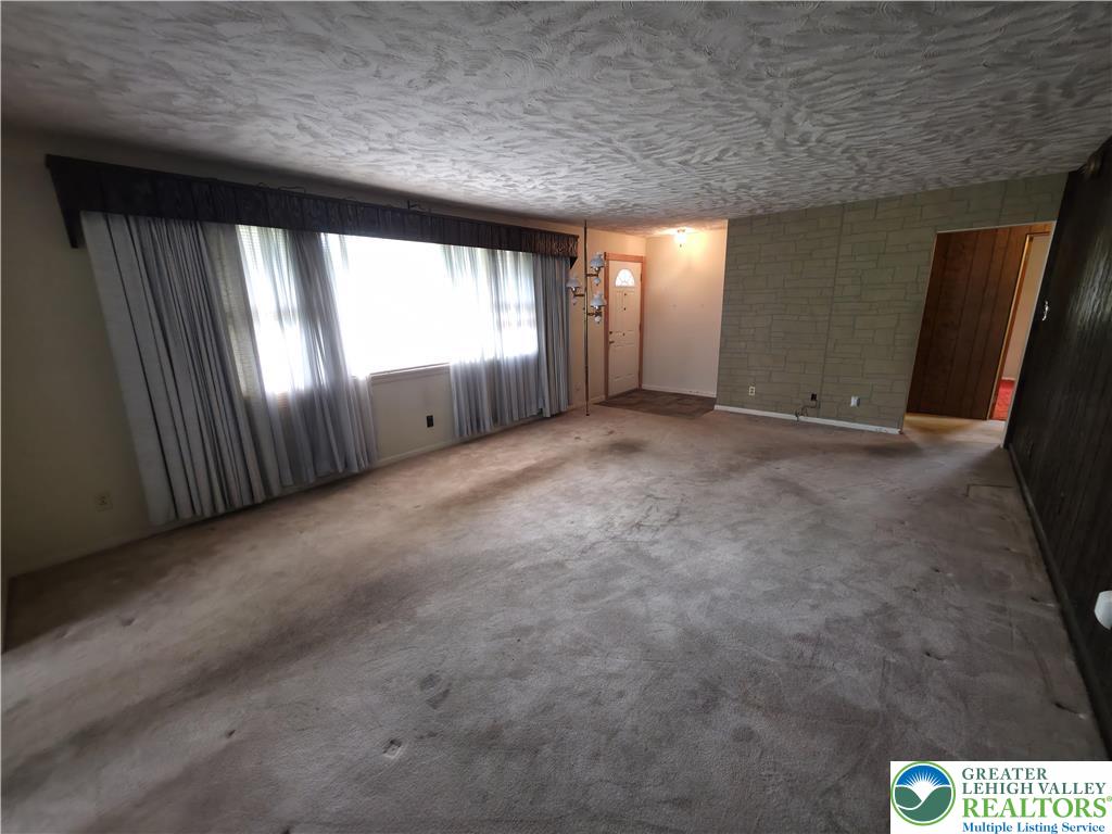50 Montovision Road Mount Pocono, PA 18344 - Photo 7 of 32 A spacious living room features ample natural light from wide windows and cozy carpeting.