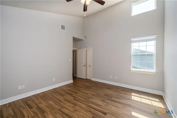 a view of an empty room with wooden floor and a window