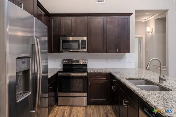 a view of cabinets a sink and dishwasher with wooden floor