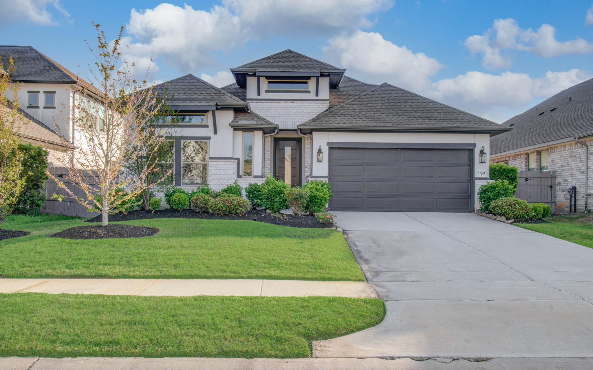 17344 Grand Canyon Road Conroe, TX 77302 - Photo 2 of 49 This photo showcases a modern, single-story home with a well-maintained front yard, featuring a two-car garage and attractive landscaping. The exterior has a neutral color palette and a welcoming entrance.