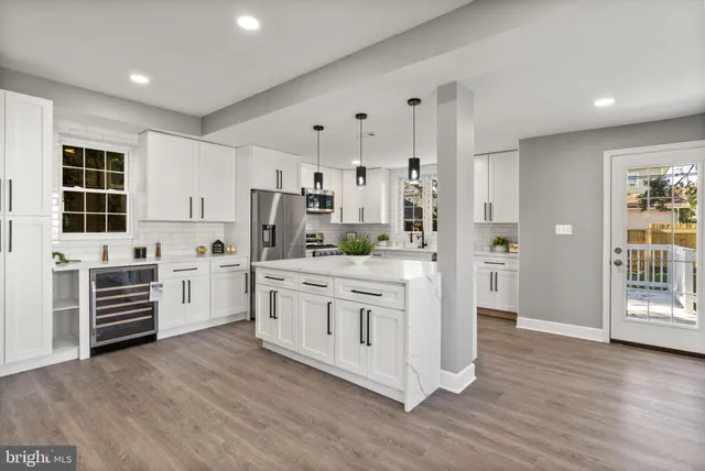 a kitchen with stainless steel appliances a stove a refrigerator and white cabinets with wooden floor