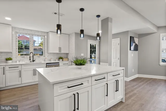 a kitchen with stainless steel appliances a sink dishwasher a refrigerator a stove top oven a kitchen island with wooden floor and cabinets