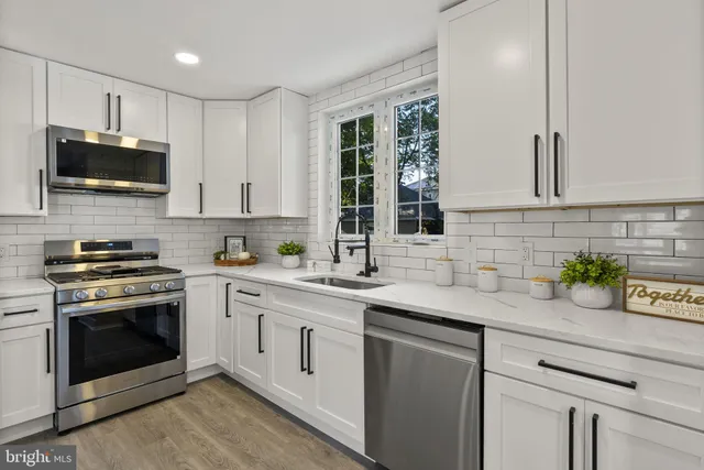 a kitchen with stainless steel appliances white cabinets and a window