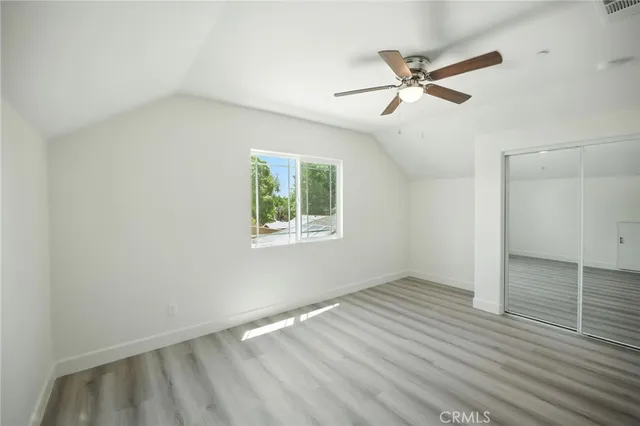 an empty room with wooden floor fan and windows