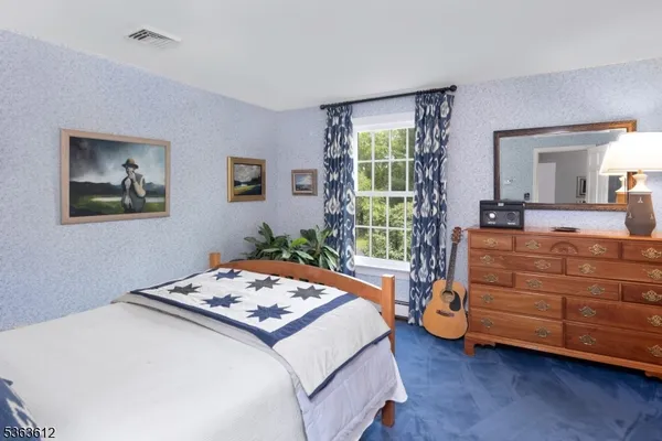 a bedroom with a bed and a dresser next to a window