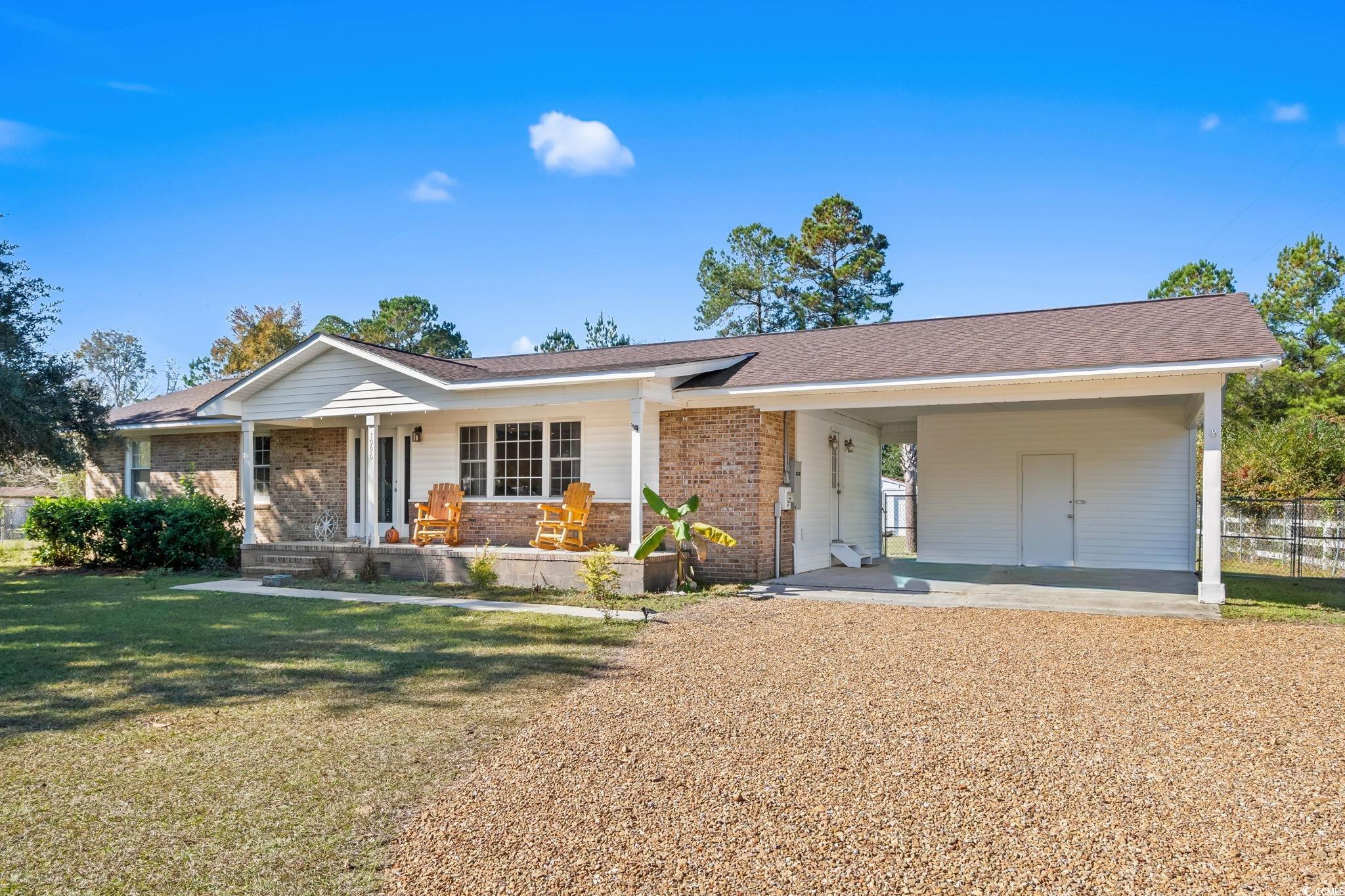1996 Heritage Road Loris, SC 29569 - Photo 1 of 40 View of front facade featuring brick siding, covered porch, a front yard, and a shingled roof
