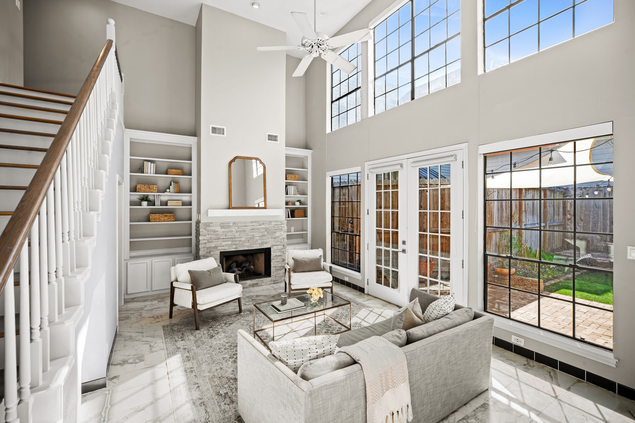 Dramatic double-height ceilings and floor-to-ceiling windows define this impressive living area. French doors provide seamless access to the private backyard, creating effortless indoor-outdoor flow.