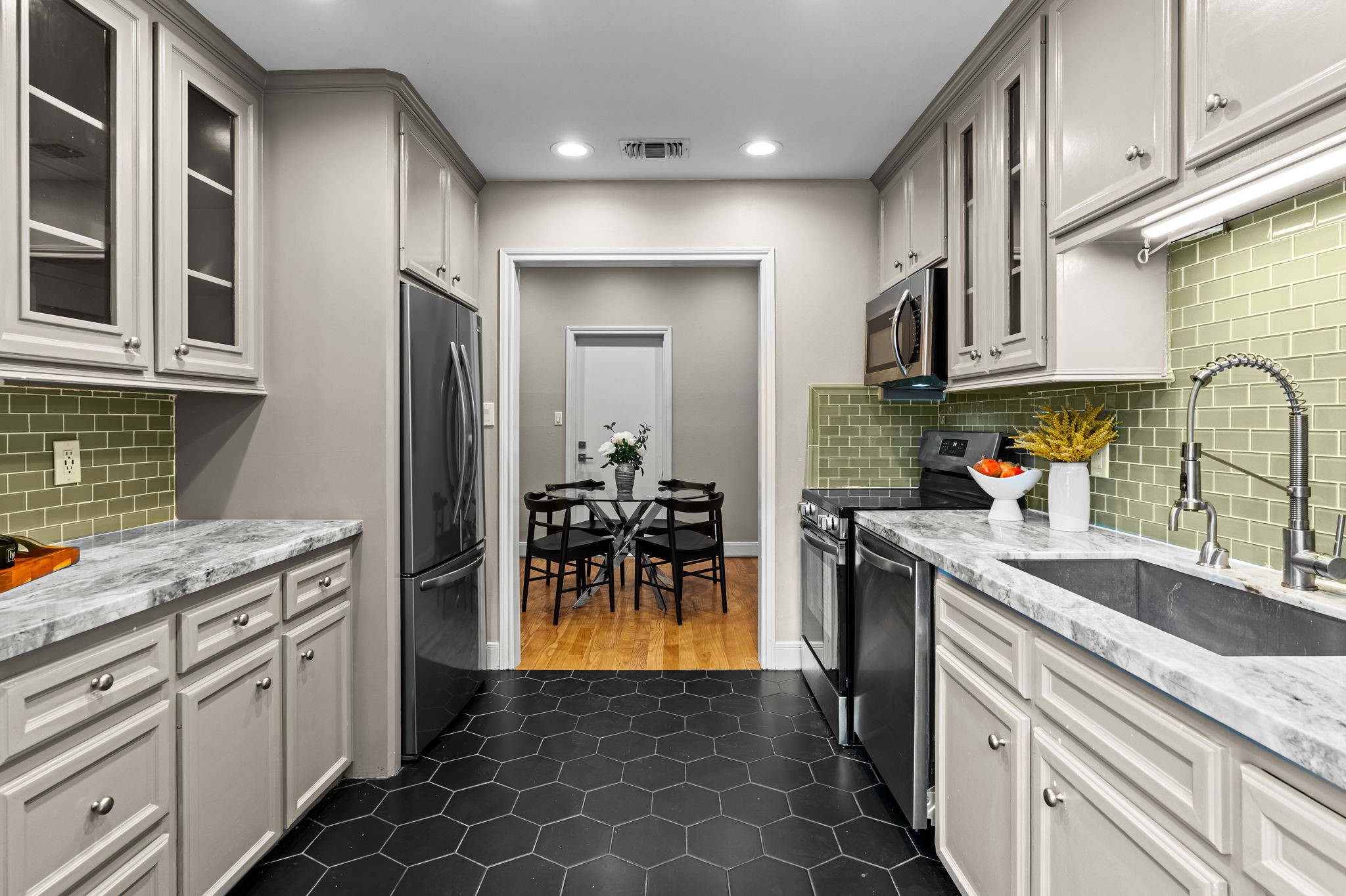 254 East 5th Street Houston, TX 77007 - Photo 3 of 31 Kitchen features elegant granite countertops, stainless steel appliances, and abundant upper and lower cabinetry for storage. A modern tile backsplash and under-cabinet lighting add warmth and contrast, while the efficient layout offers seamless access to the adjacent dining area for easy everyday living and entertaining