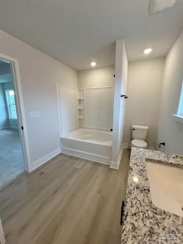 a bathroom with a granite countertop sink a toilet and shower