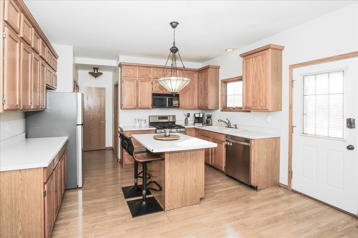 944 1st Street, Unit 944 Batavia, IL 60510 - Photo 8 of 26 a kitchen with a refrigerator a sink dishwasher a stove and a dining table with wooden floor