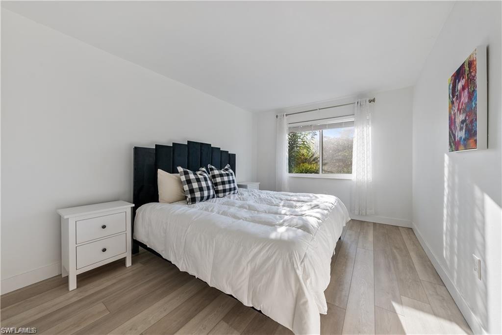 72 7th Street South, Unit 310 Naples, FL 34102 - Photo 11 of 20 a bedroom with a bed and wooden floor