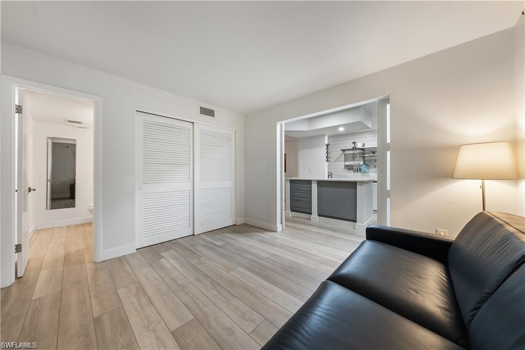 72 7th Street South, Unit 310 Naples, FL 34102 - Photo 15 of 20 a view of a livingroom with a flat screen tv wooden floor and kitchen