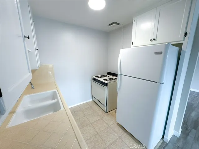 a kitchen with a refrigerator a stove top oven and cabinets